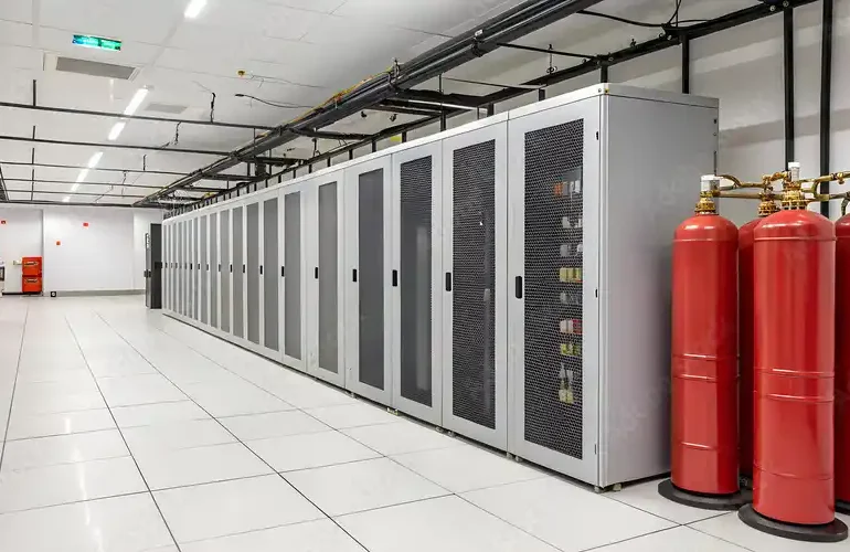 A row of server cabinets in a data center with red fire extinguishers on the side.