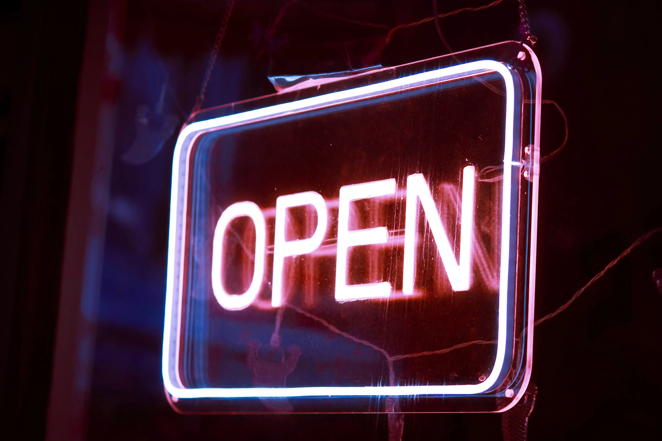 A glowing neon "OPEN" sign illuminated in red and blue against a dark background.