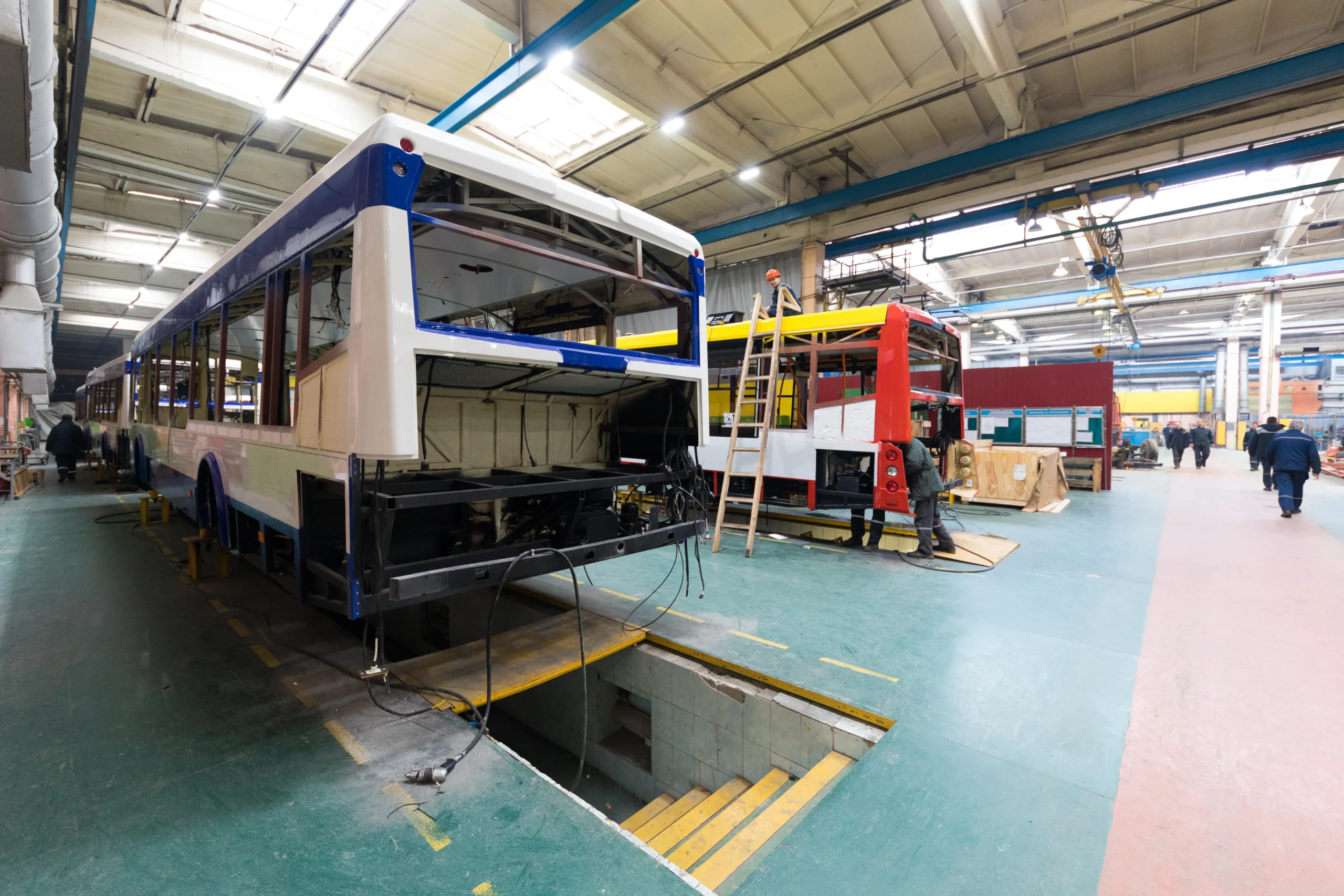 A spacious manufacturing workshop where food trucks are being built, showcasing the process of constructing custom food service vehicles for restaurants and catering businesses.