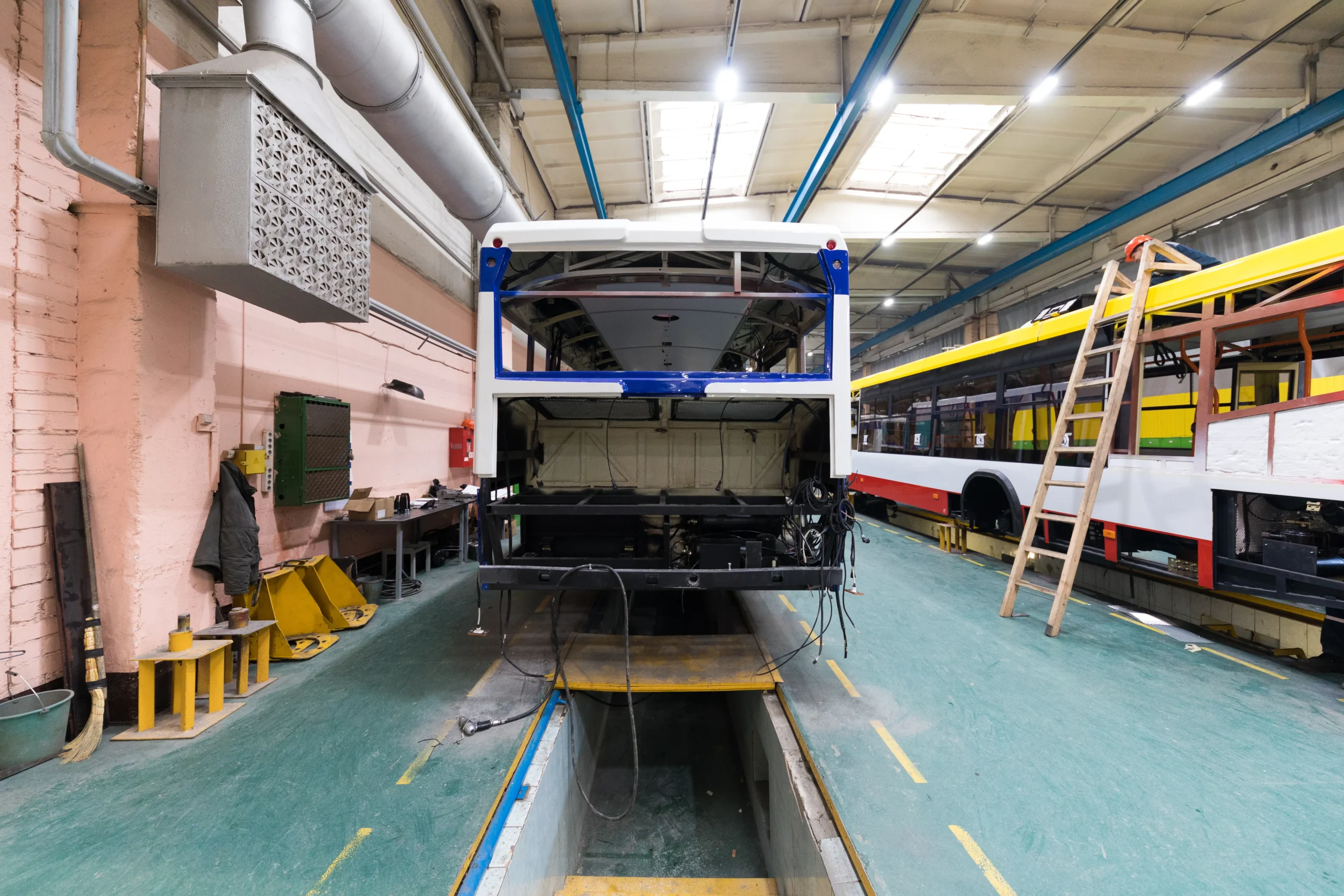 A spacious manufacturing workshop where food trucks are being built, showcasing the process of constructing custom food service vehicles for restaurants and catering businesses.