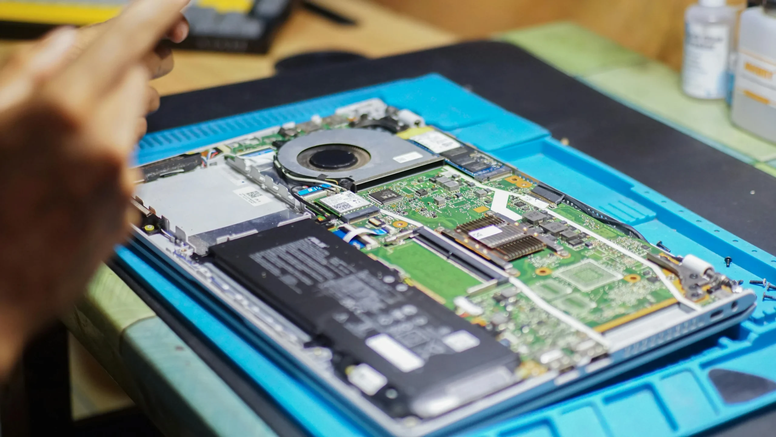 A technician carefully working on the internal components of a laptop, performing maintenance or repair to ensure optimal performance, highlighting the expertise in electronic device servicing.