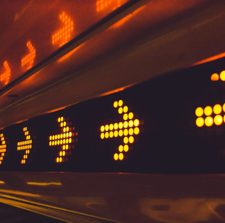 Close-up of a row of illuminated orange arrows on a LED display, indicating direction.