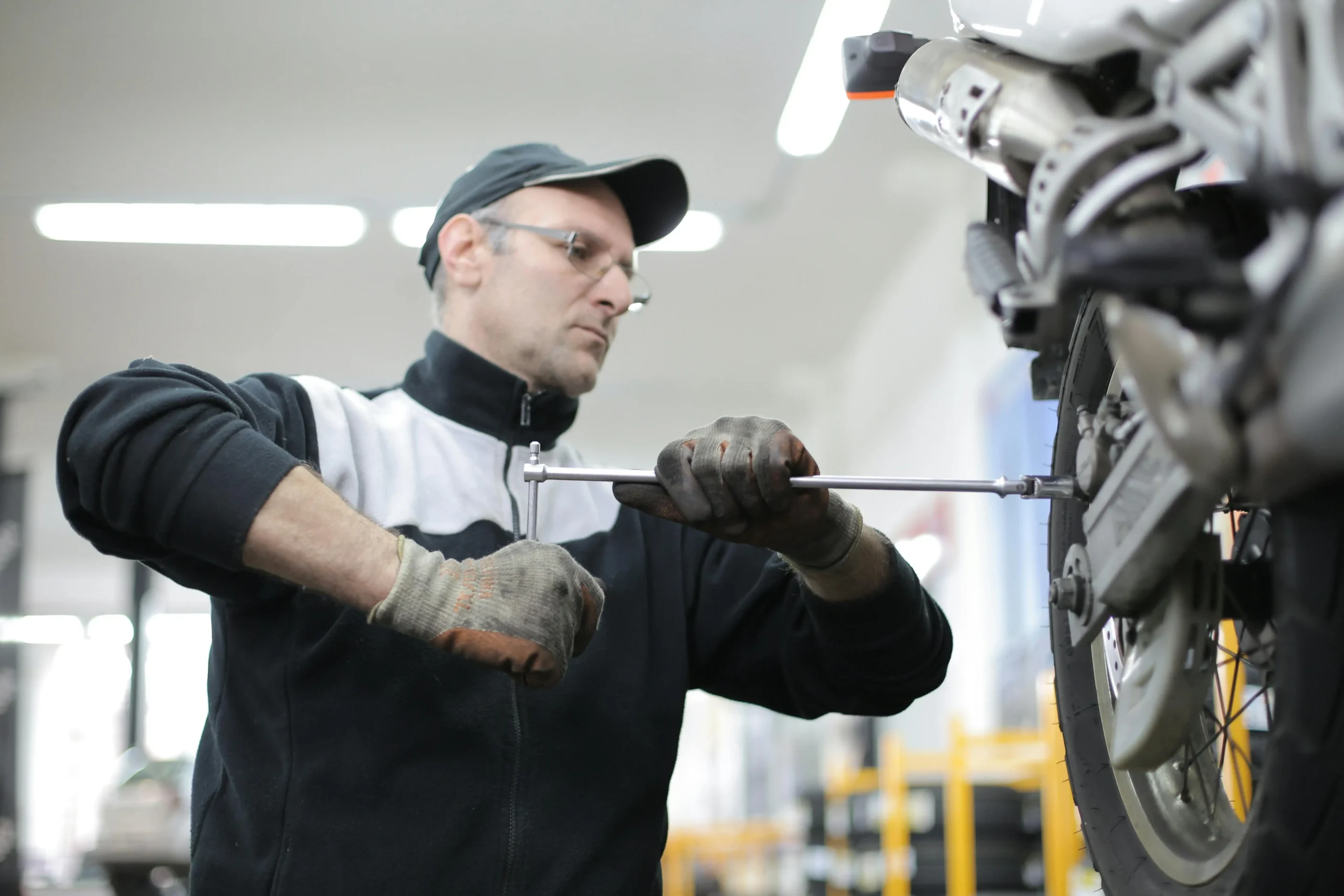 A professional technician working with a wrench on a motorcycle in a well-equipped workshop, highlighting the skilled craftsmanship in mechanical repair services.