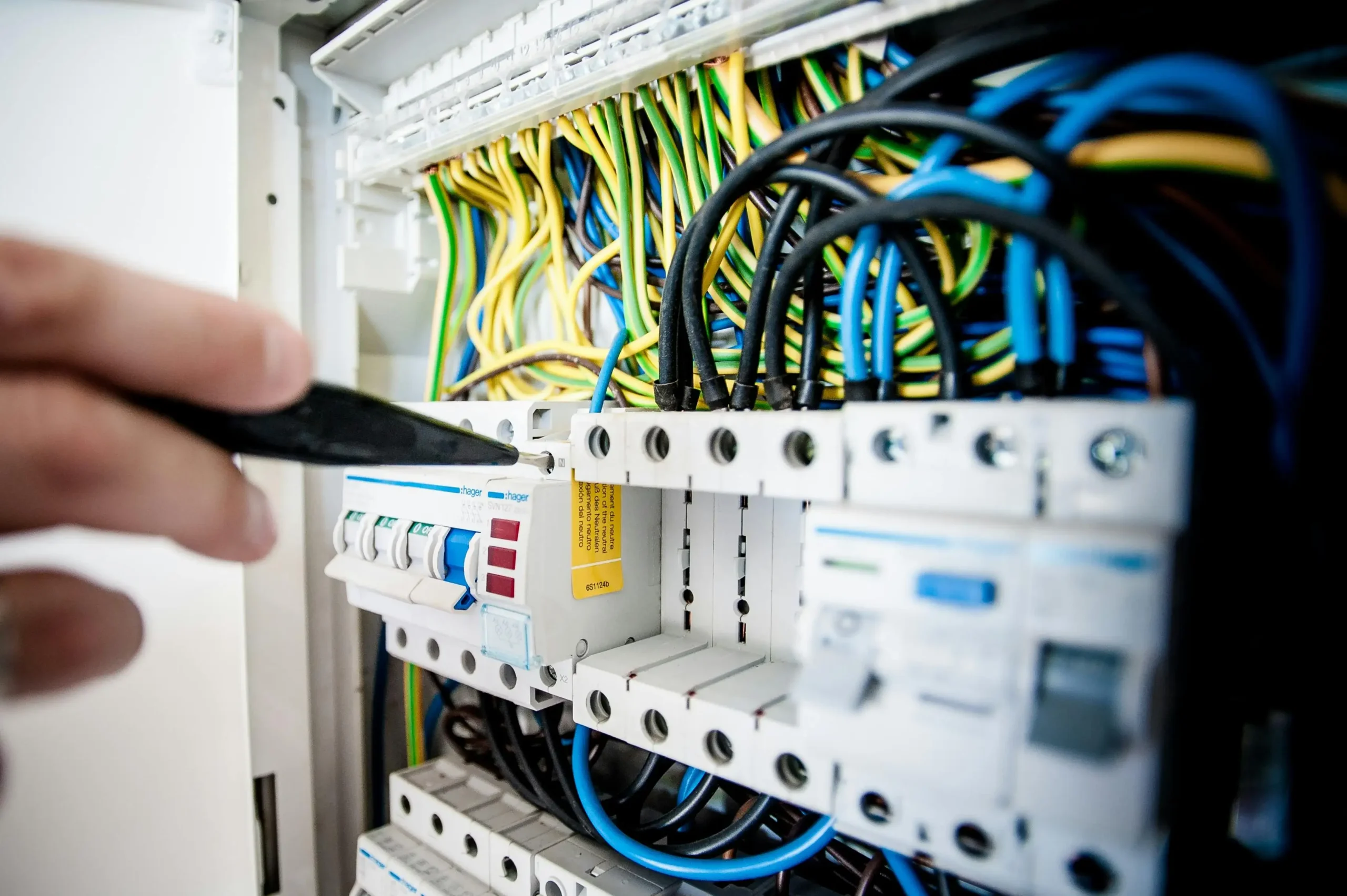 An electrician working on a circuit breaker panel, ensuring proper wiring and connections for safe electrical systems in a restaurant or commercial setting.