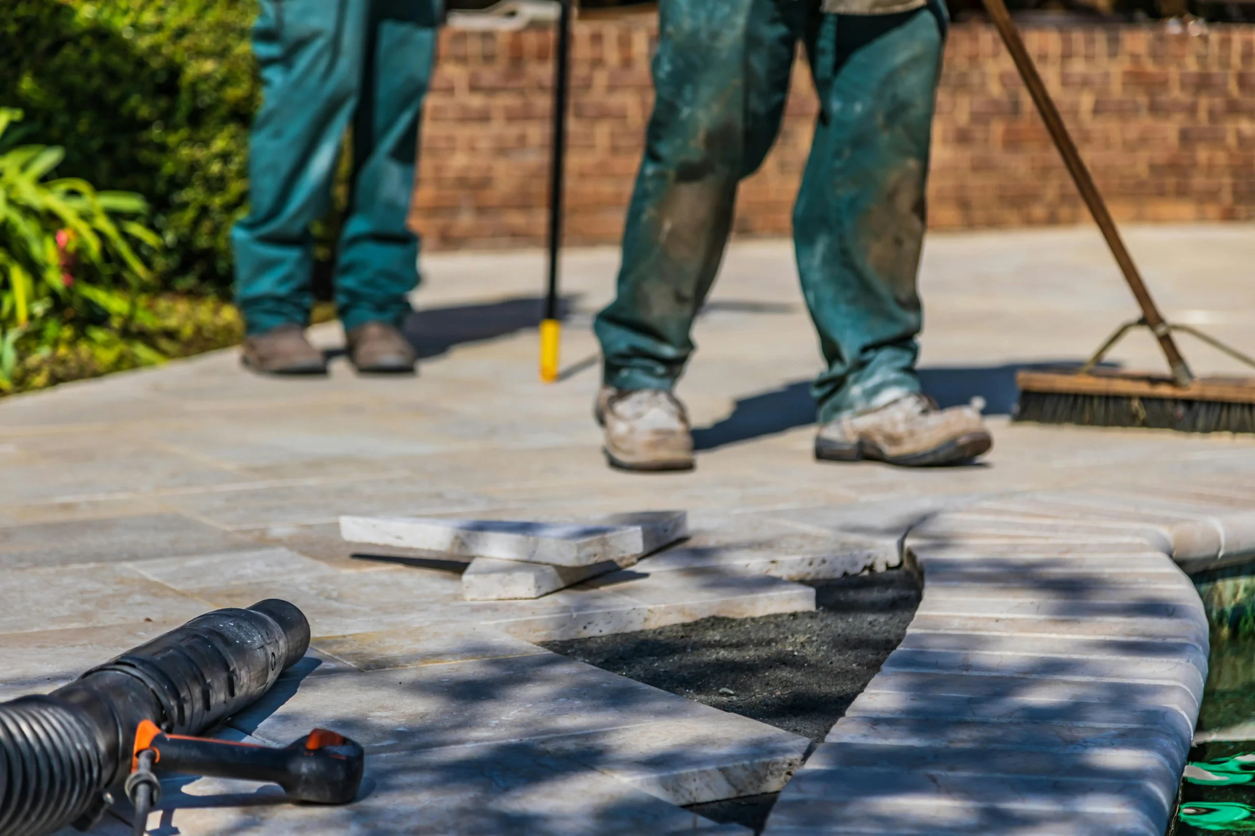 Workers laying paving stones and cleaning up the area, ensuring a neat and sturdy outdoor flooring installation, ideal for restaurant patios and exterior spaces.
