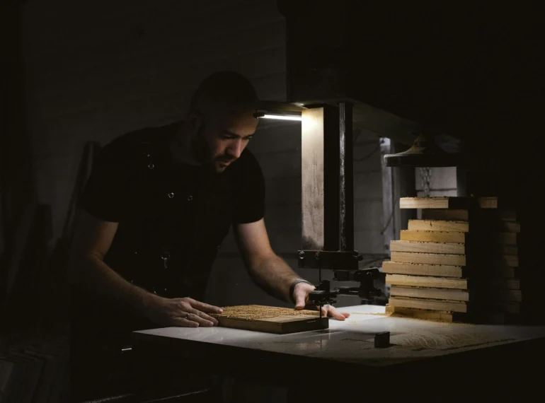 A skilled craftsman working with a press machine to shape wooden pieces, essential for creating custom furniture and fixtures for restaurant interiors.