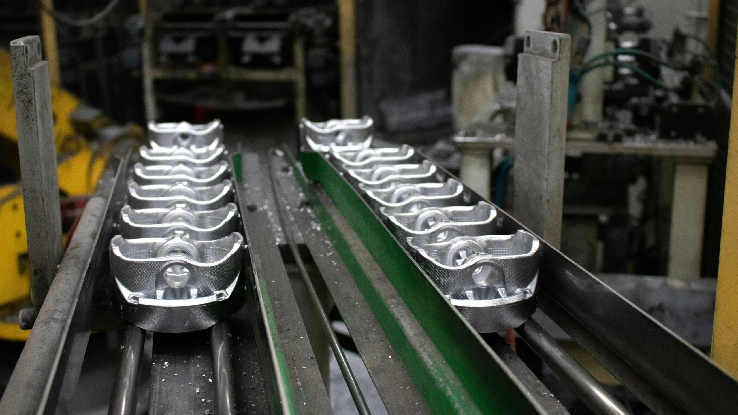A close-up view of metal components on a production line, showcasing precision manufacturing for customized equipment used in restaurant kitchens and food service setups.